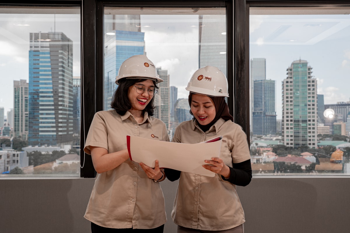 Two engineers in hard hats reviewing a document together