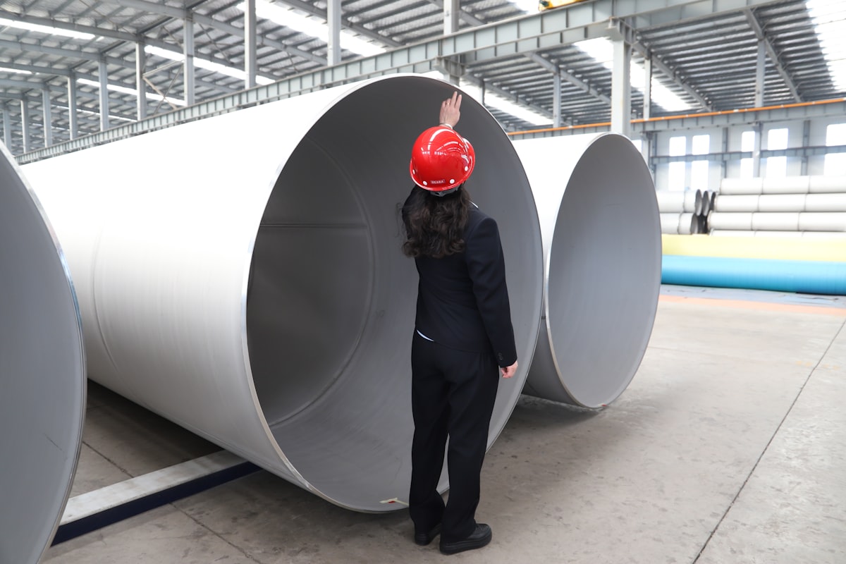 Engineer in a hard hat inspecting large industrial pipes